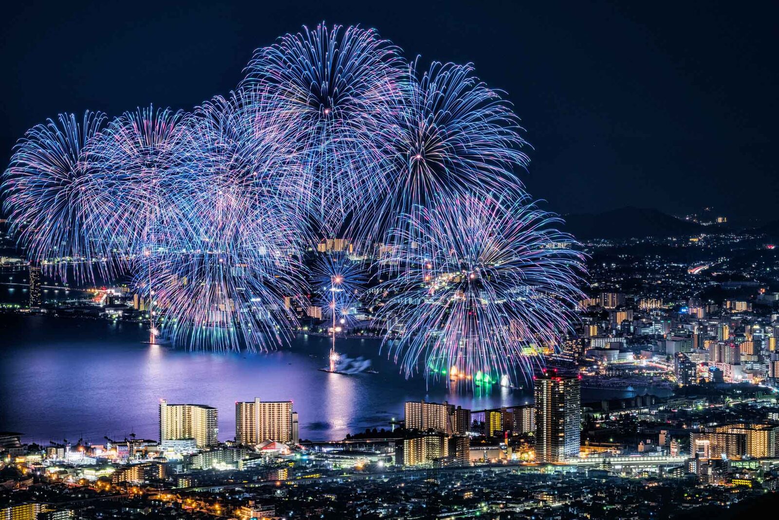 Fireworks over a lakeside city at night