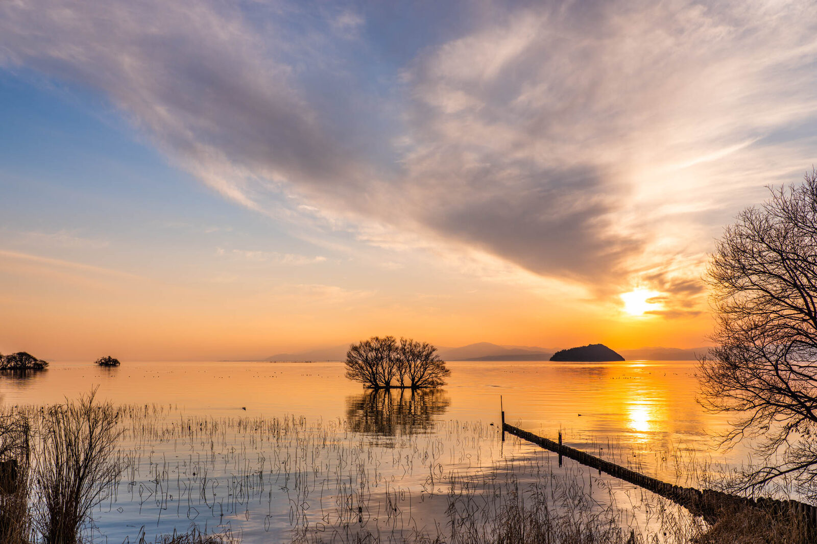 Sunrise over a calm lake with mooring poles